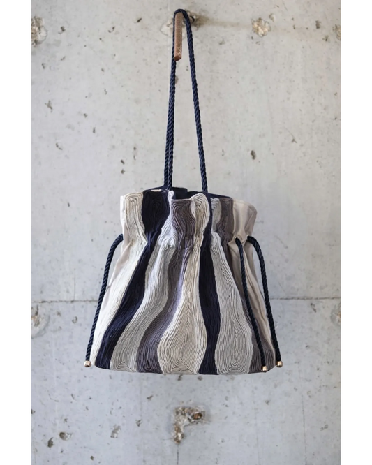 Farah Daylac cream, grey, and navy striped pouch bag with rope handle and gold hardware.