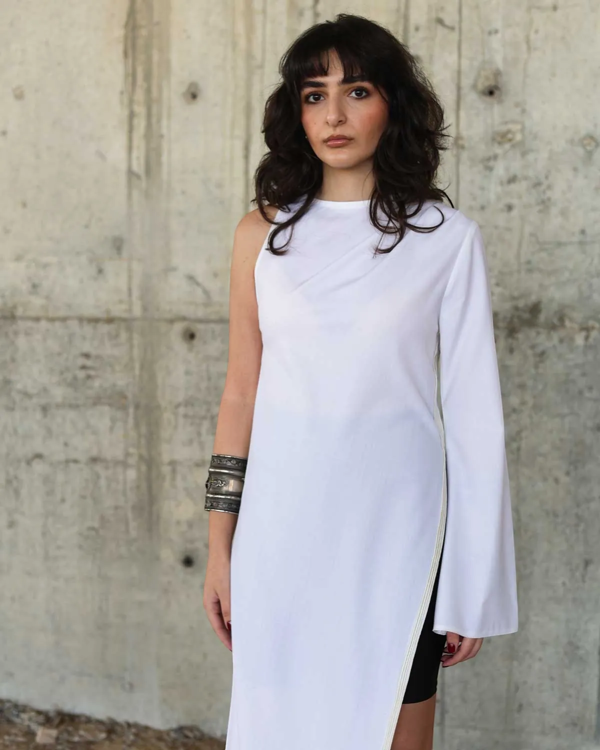 Farah Daylac white cotton one-sleeve dress with flared cuff and side slit. Editorial style.